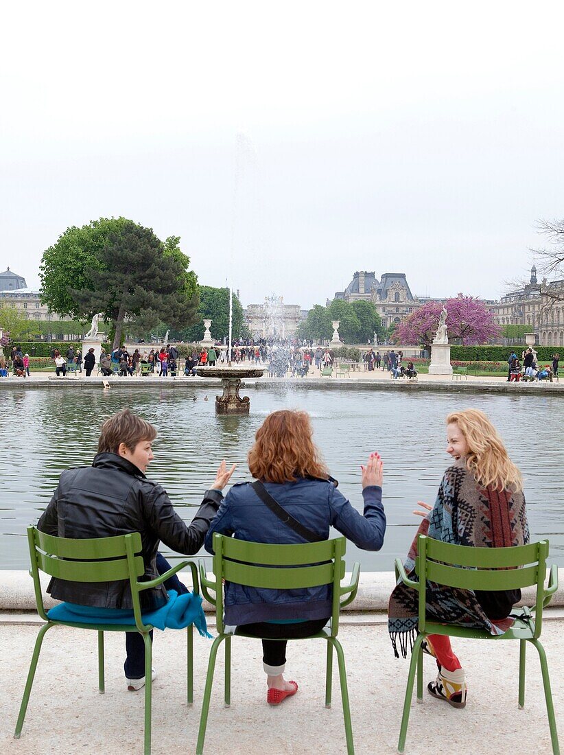 Friends relax around a fountain at the Tuileries Gardens (Jardin des Tuileries) in spring, Paris, France, Europe.