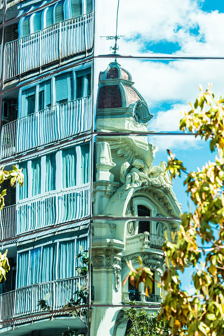 A residential building and an old building reflected in the front of an office house in the city centre, Granada, Andalusia, Spain