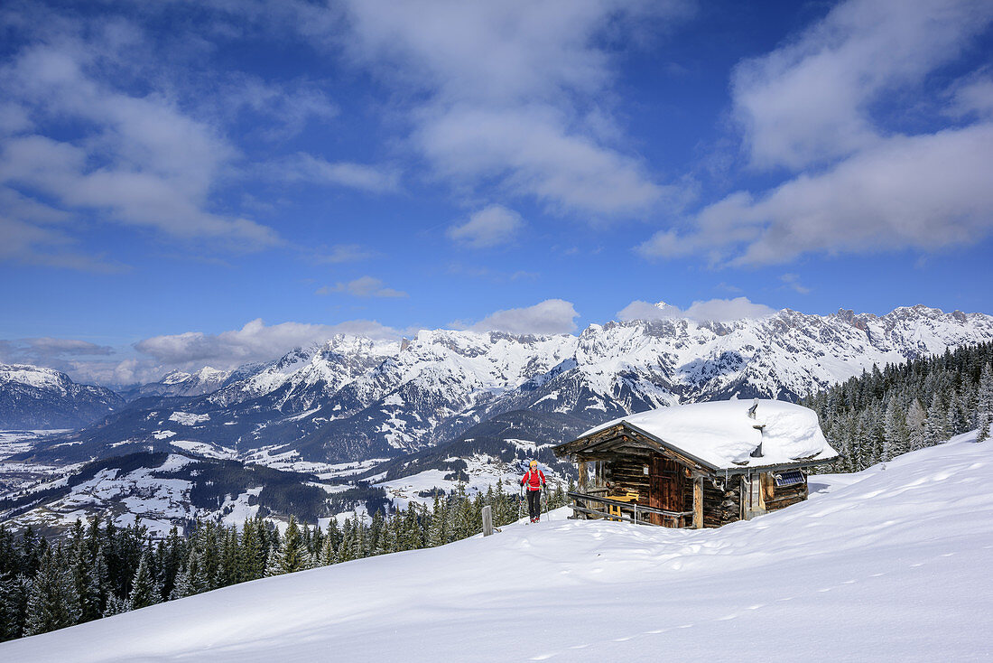 Frau auf Skitour steigt an Alm vorbei zum Hochkasern auf, Berchtesgadener Alpen im Hintergrund, Hochkasern, Salzburger Schieferalpen, Dientner Schieferberge, Salzburg, Österreich