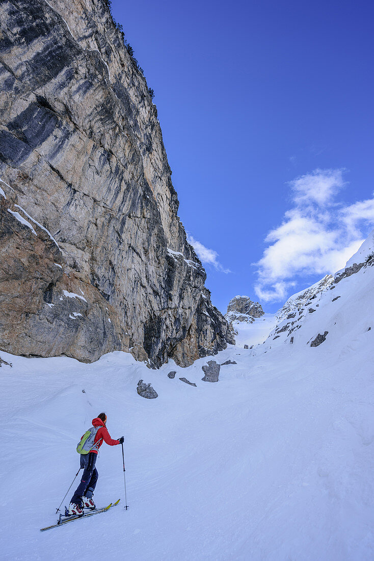 Woman back-country skiing passing rockfaces and ascending to Cresta Bianca, Cresta Bianca, Monte Cristallo, Dolomites, UNESCO World Heritage Dolomites, Venetia, Italy