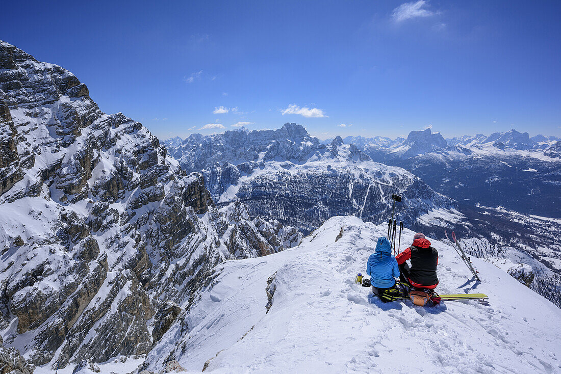 Zwei Personen auf Skitour sitzen am Gipfel der Cresta Bianca, Blick auf Sorapis und Pelmo, Cresta Bianca, Monte Cristallo, Dolomiten, UNESCO Weltnaturerbe Dolomiten, Venetien, Venezien, Italien