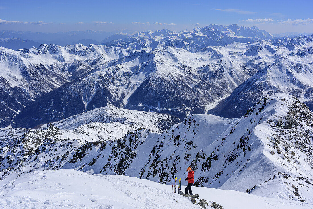 Woman back-country skiing having a break, Ortler Range and Bernina Range in background, Hasenoehrl, valley of Ultental, Ortler Range, South Tyrol, Italy
