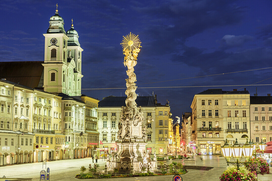 Illuminated city square with Old Cathedral and pillar Dreifaltigkeitssäule, Linz, Danube Bike Trail, Upper Austria, Austria