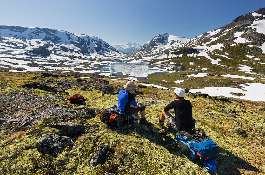 zwei Wanderer sitzend auf ihren Rucksäcken, Blick ins Gravdalen, Jotunheimen Nationalpark, Sogn og Fjordane, Norwegen