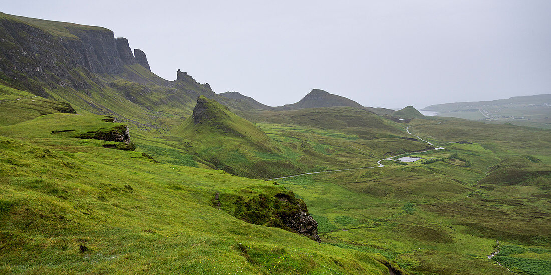 'Fog over the lush green landscape with cliffs and peaks; Staffin, Scotland'