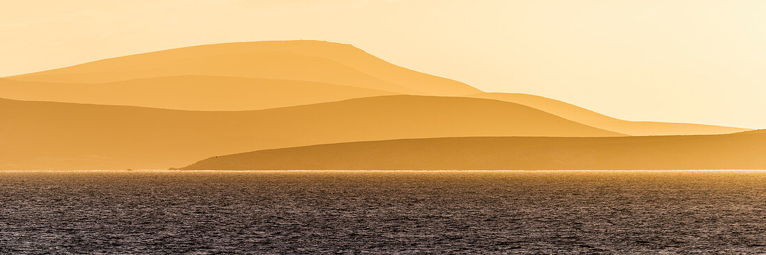 'Sunrise over orange hills and blue ocean; Antarctica'