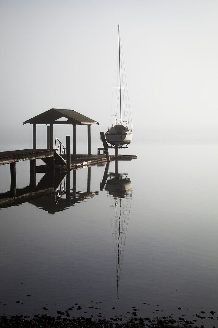 'Sailboat on lift by dock on foggy lake; Bellingham, Washington, United States of America'