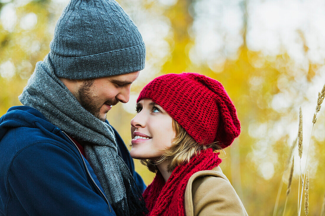 'A young couple looking into each other's eyes in a city park in autumn; Edmonton, Alberta, Canada'
