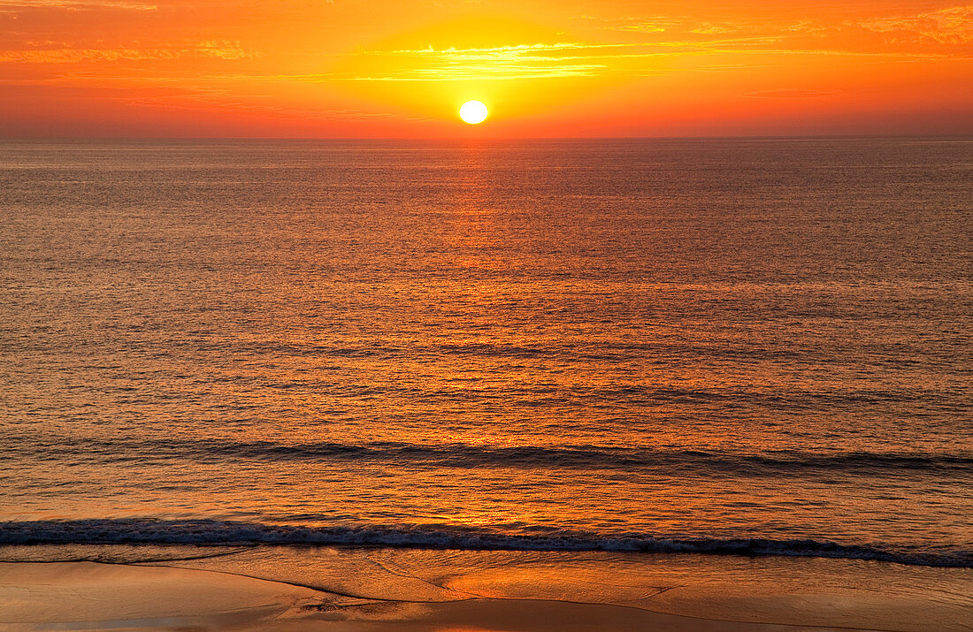 'A golden sun sinking into the horizon over the ocean; Andalusia, Spain'