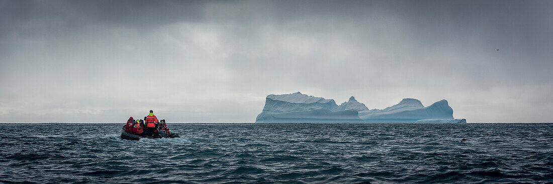 'Inflatable motors towards blue iceberg on horizon; Antarctica'