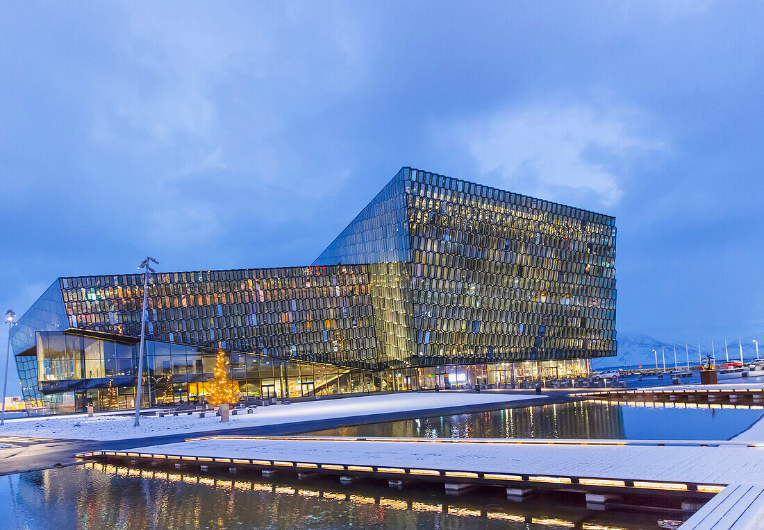 'Exterior view of the Harpa Public Concert Hall, designed by the Danish firm Henning Larsen Architects and Icelandic firm Batteriao Architects, the glass facade was designed by Icelandic glass artist Olafur Eliasson at twilight; Reykjavik, Iceland'