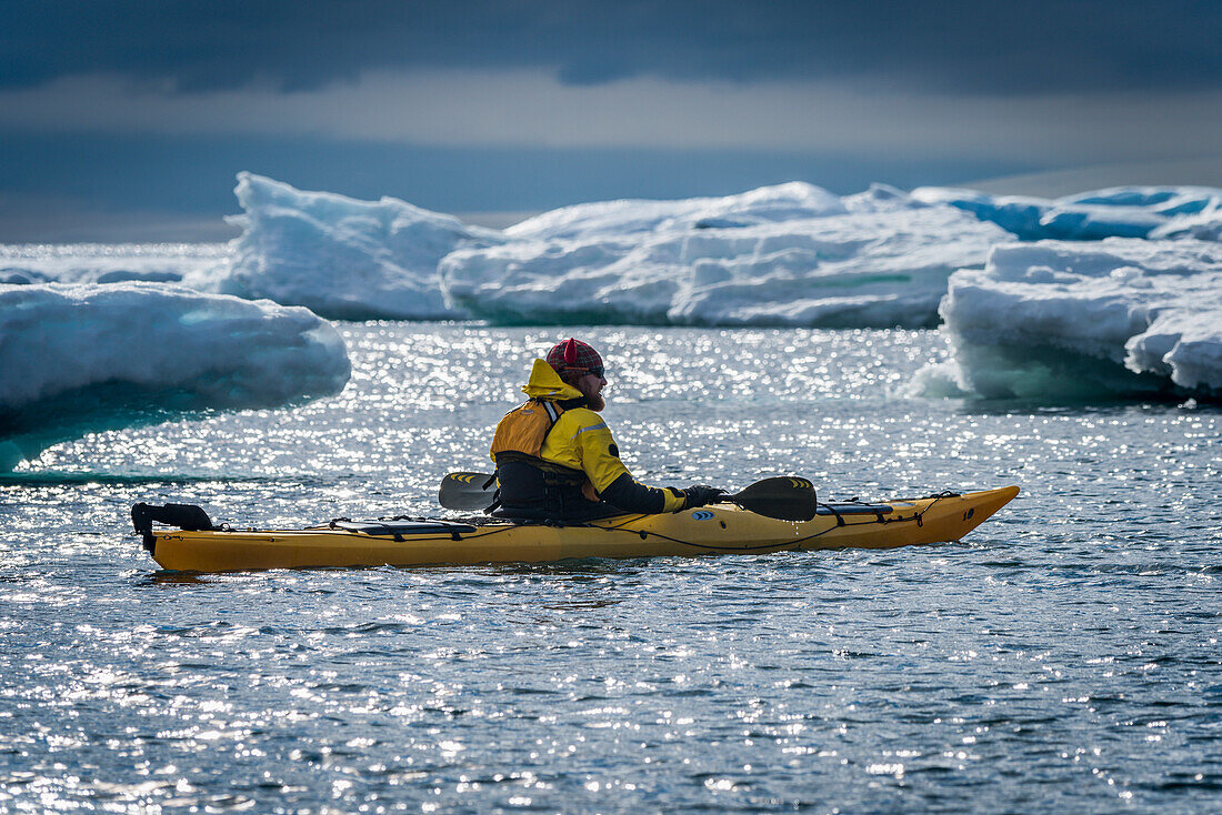 'Kayaker surrounded by icebergs resting his paddle; Antarctica'