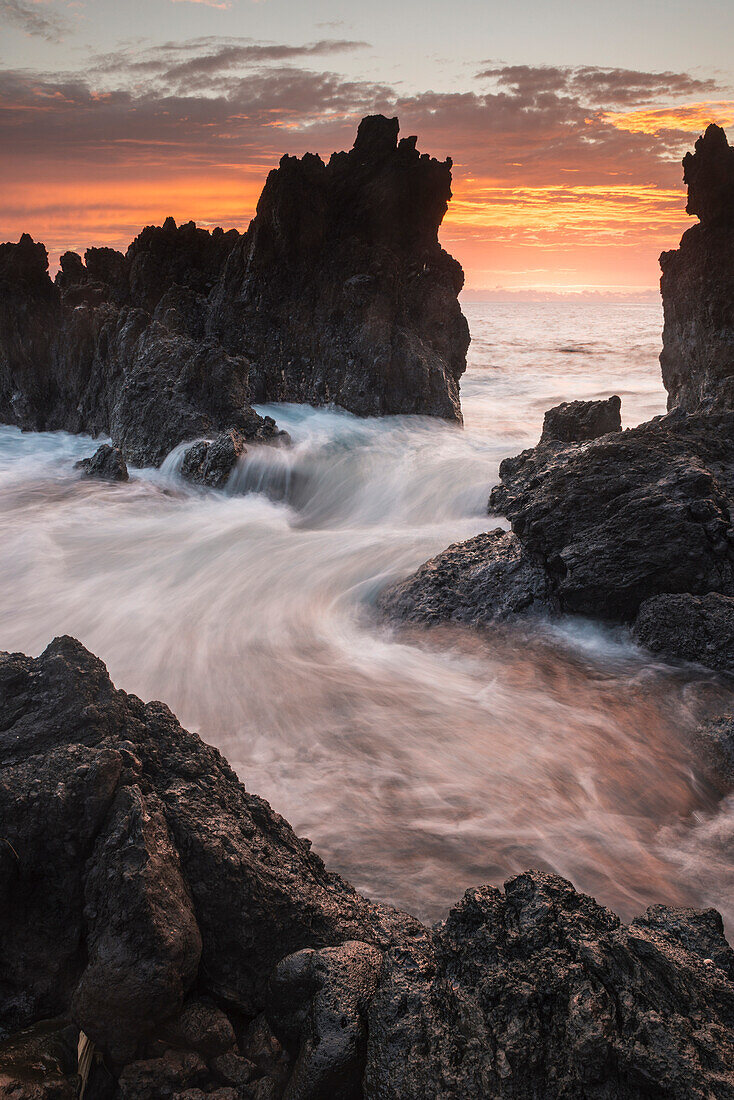 'Surf comes in through rocks at sunrise; Laupahoehoe, Island of Hawaii, Hawaii, United States of America'