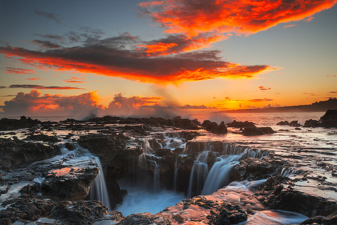 'Surf spills into a hole in a rock outcrop at sunrise on the east side of Kauai; Kauai, Hawaii, United States of America'