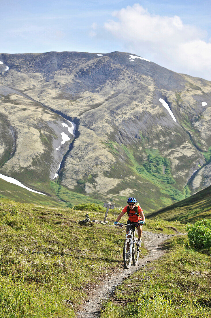 Woman rides a full suspension mountain bike on the Resurrection Pass Trail in the Chugach National Forest, Kenai Peninsula, South-central Alaska