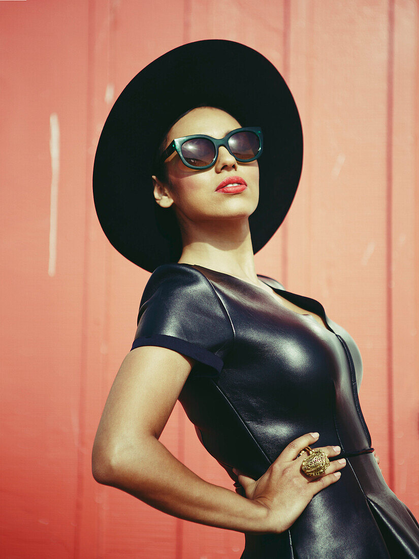 Porträt einer modischen Frau in schwarzem Lederkleid, Hut und Sonnenbrille