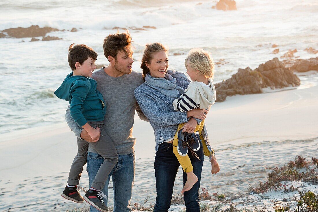 Happy young family enjoying on the beach at sunset