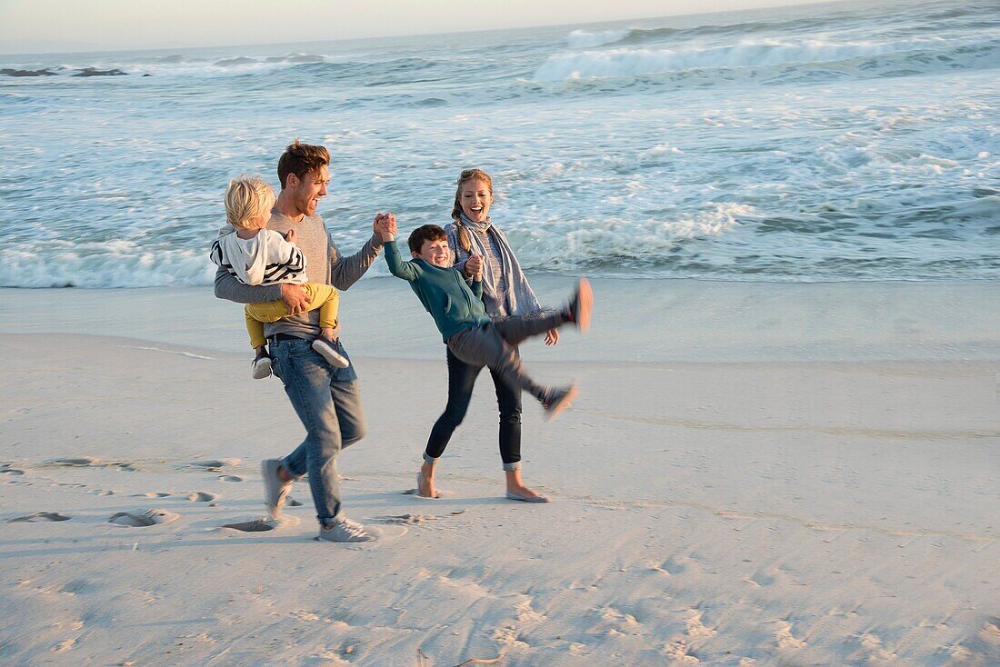 Happy young family having fun on the beach at sunset