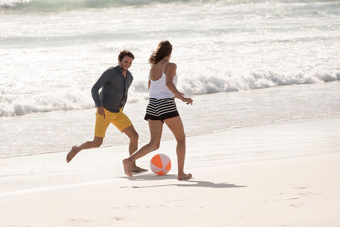 Happy young couple playing with a beach ball