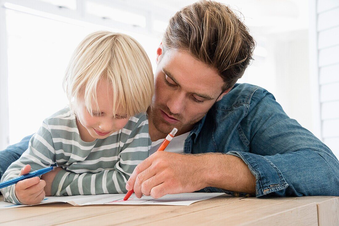Father and son doing homework on table