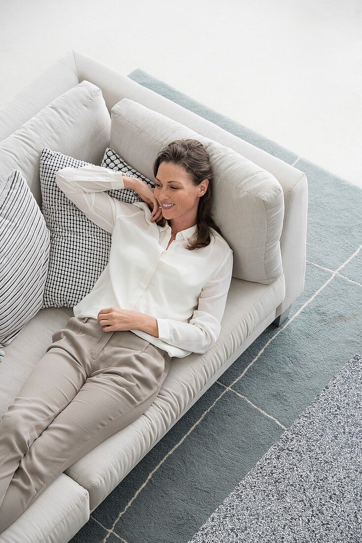 Happy mature woman lying on couch