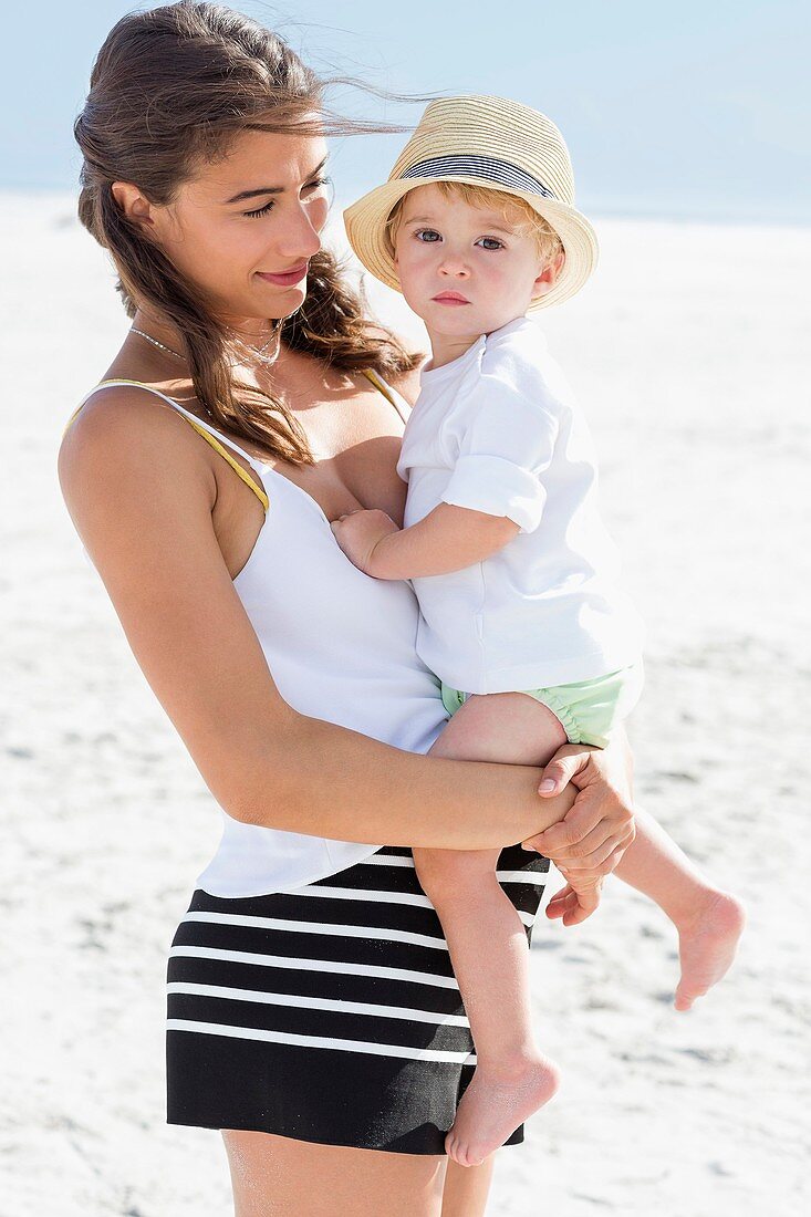 Beautiful woman carrying her son on the beach