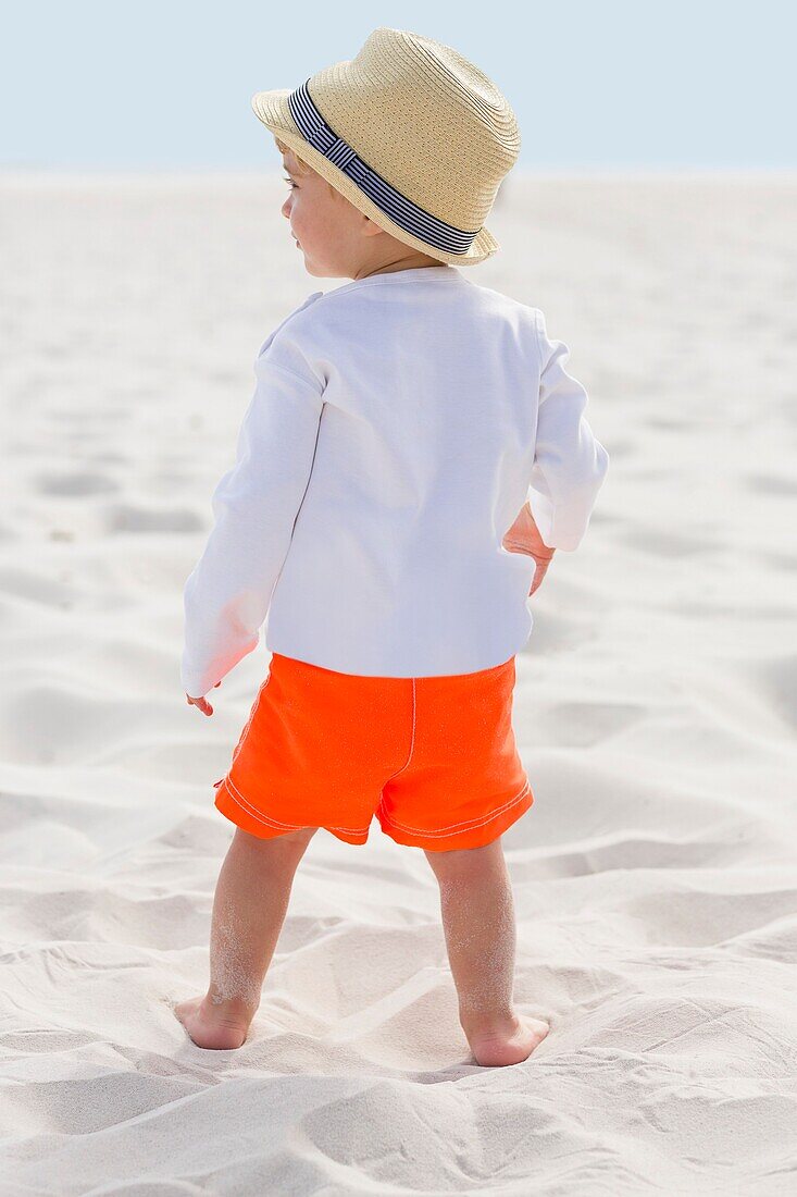 Rear view of a baby boy standing on the beach