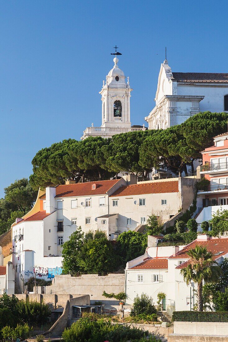 View of a residential district of Lisbon surrounded by trees and church under a blue summer sky Portugal Europe.