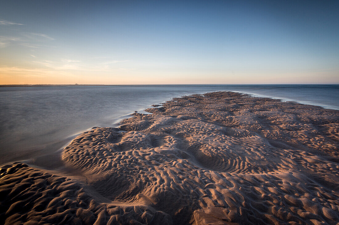 Sand formations at Budle Bay, with Holy Island Castle in the distance, Northumberland, England, United Kingdom, Europe