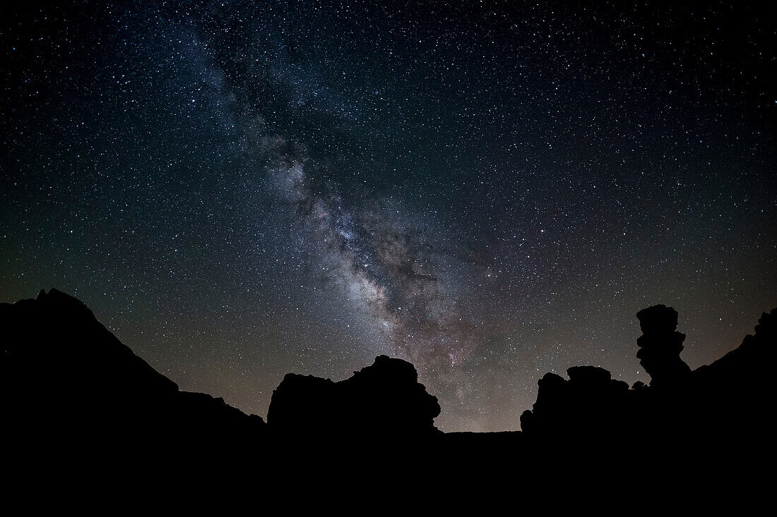 The Milky Way arches high in the night sky above Roques de Garcia in Teide National Park, UNESCO World Heritage Site, Tenerife, Canary Islands, Spain, Europe