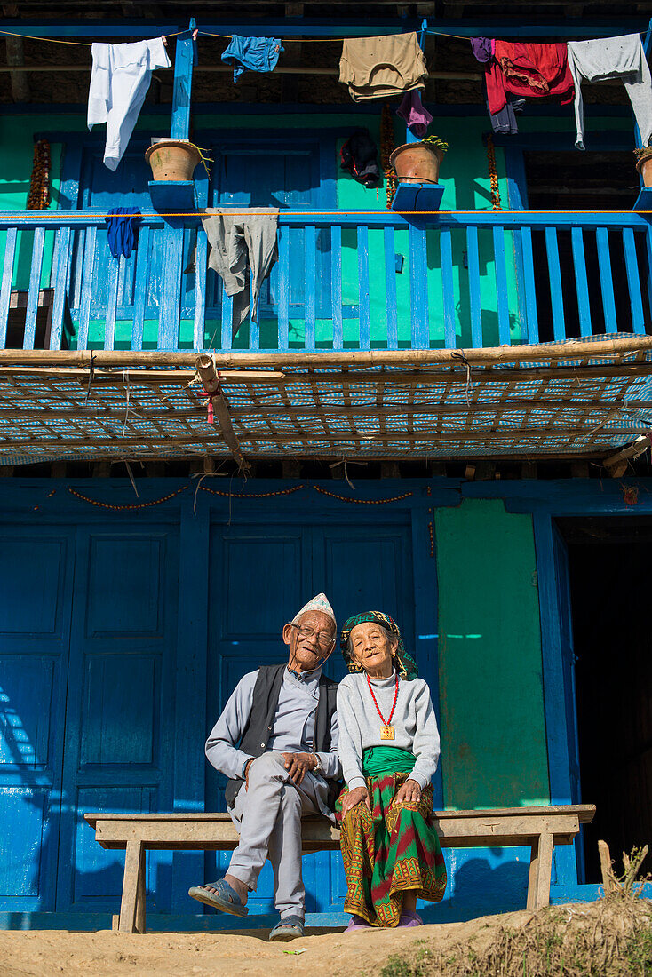 A old Nepali couple wearing traditional dress sit outside their house in Diktel, Khotang District, Nepal, Asia