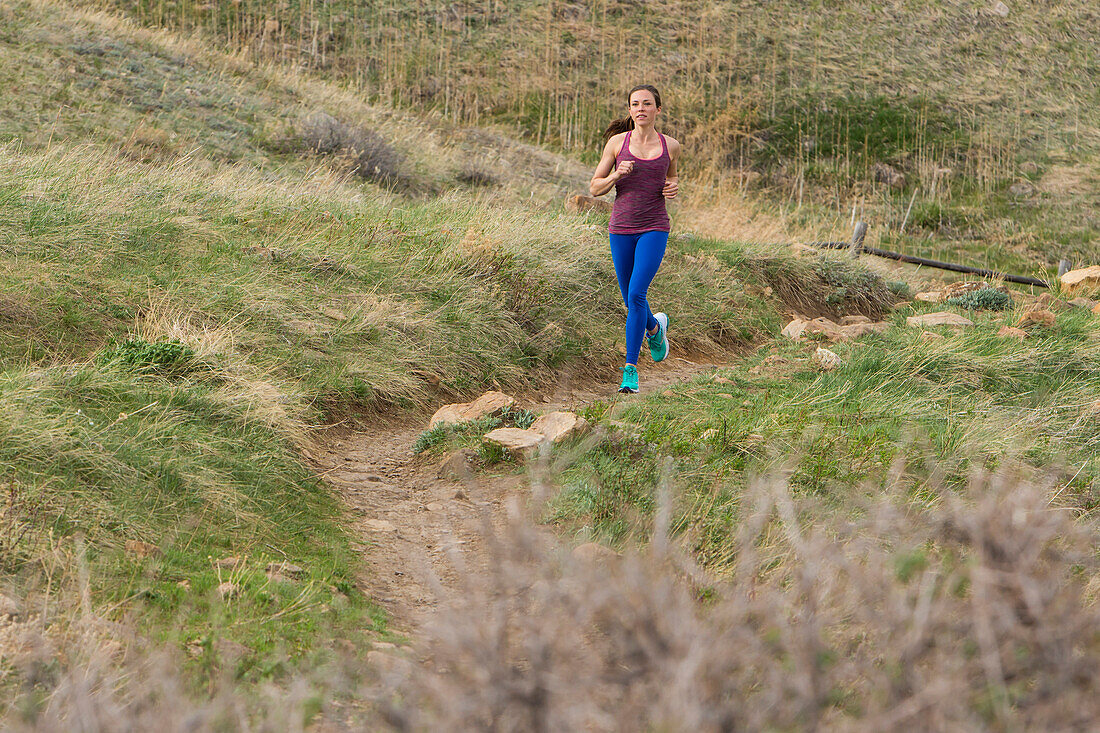 Athletic woman running on a trail through the fields of Boulder, Colorado