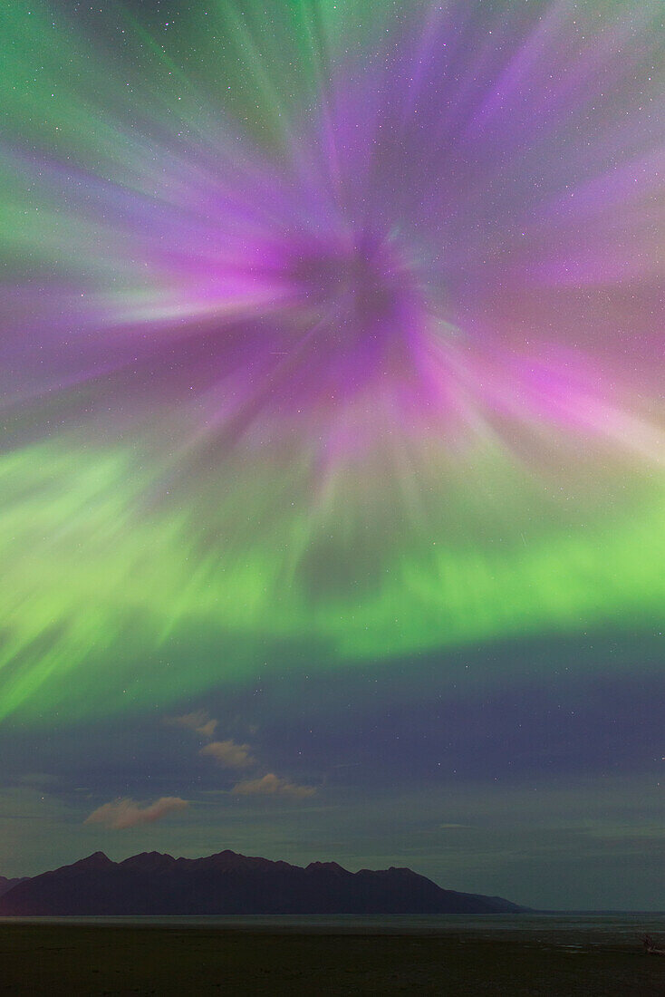The aurora borealis bursts over the Kenai Mountains and the mudflats of the Anchorage Coastal Wildlife Refuge, Southcentral Alaska
