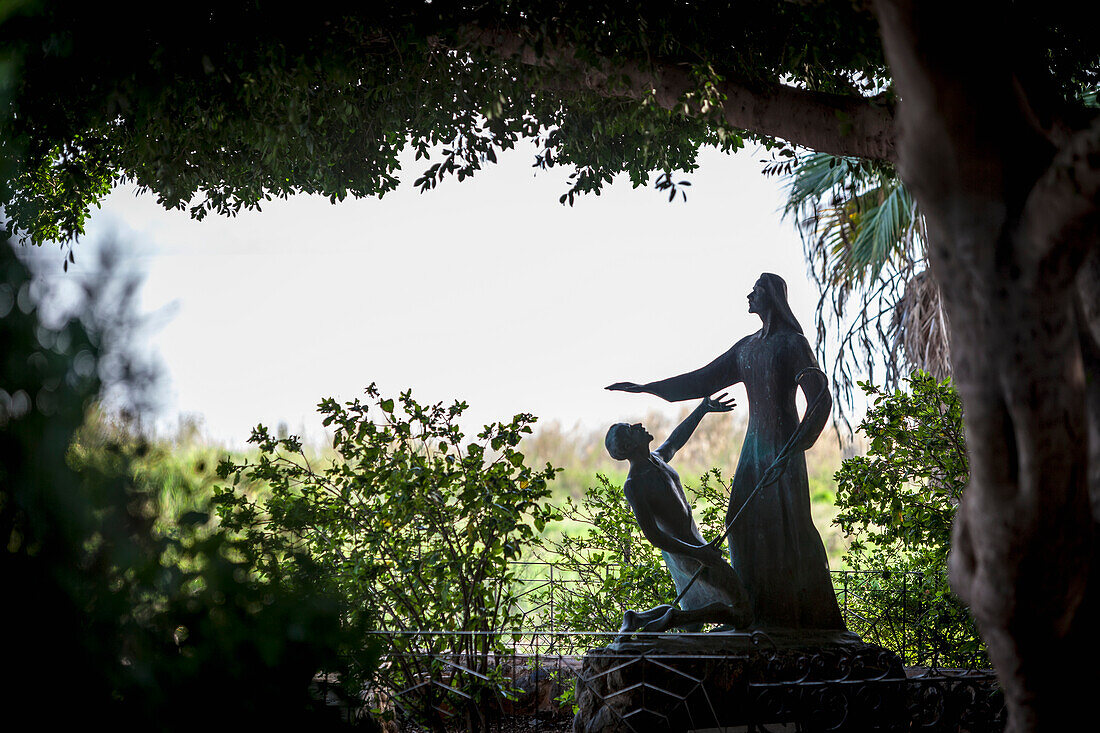 'On the Sea of Galilee, a statue beside the Church of St Peter's Primacy depicts Jesus after his death and Resurrection, appearing before St. Peter; Galilee, Israel'