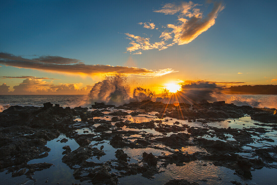 'Waves crash over a rock outcrop at sunrise; Kauai, Hawaii, United States of America'