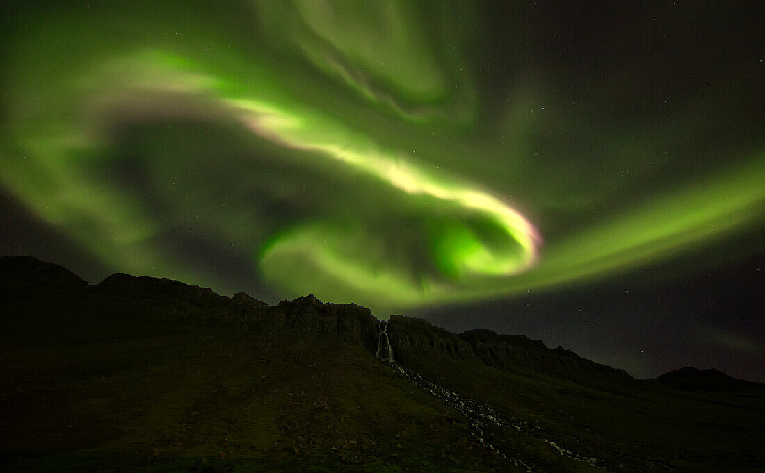 'Aurora overtop of an unnamed waterfall near the town of Djupavik; West Fjords, Iceland'