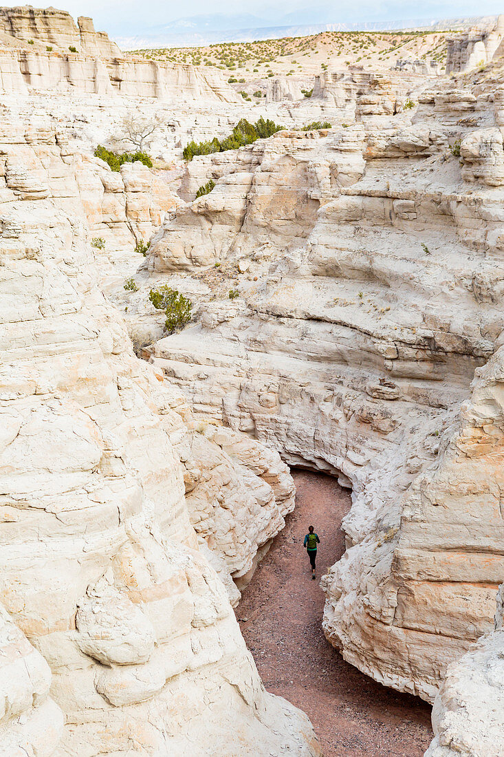 Woman running in canyon wearing backpack