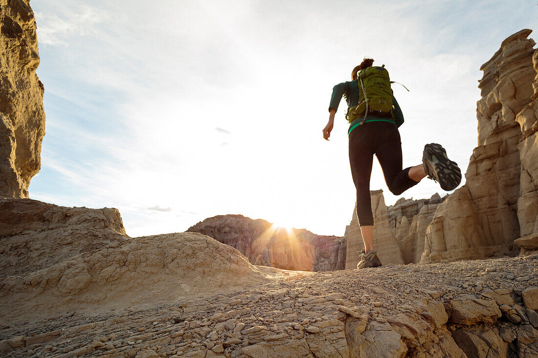 Woman running in canyon wearing backpack