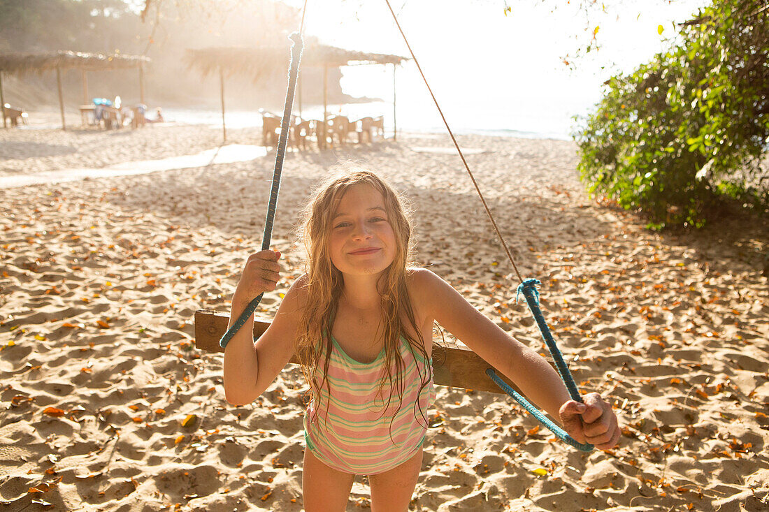 Caucasian girl playing on tree swing