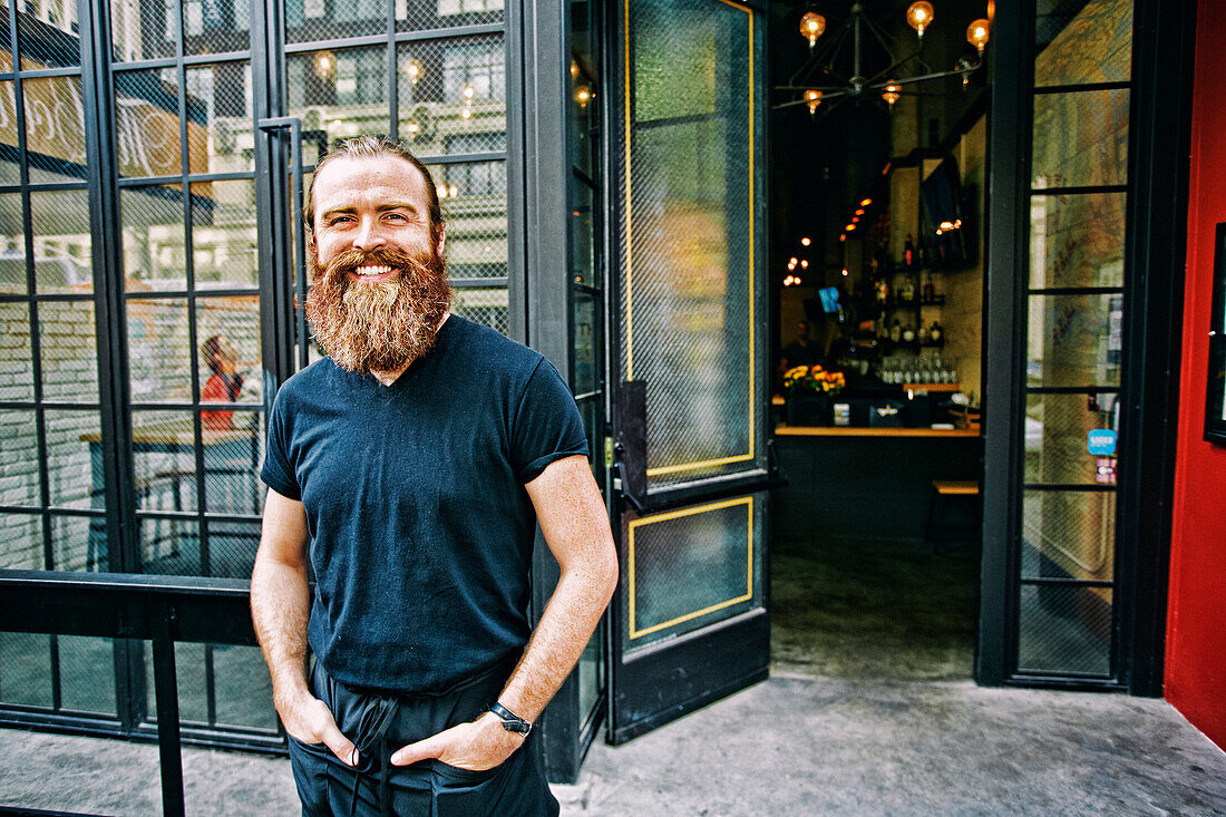 Caucasian man with beard smiling on sidewalk