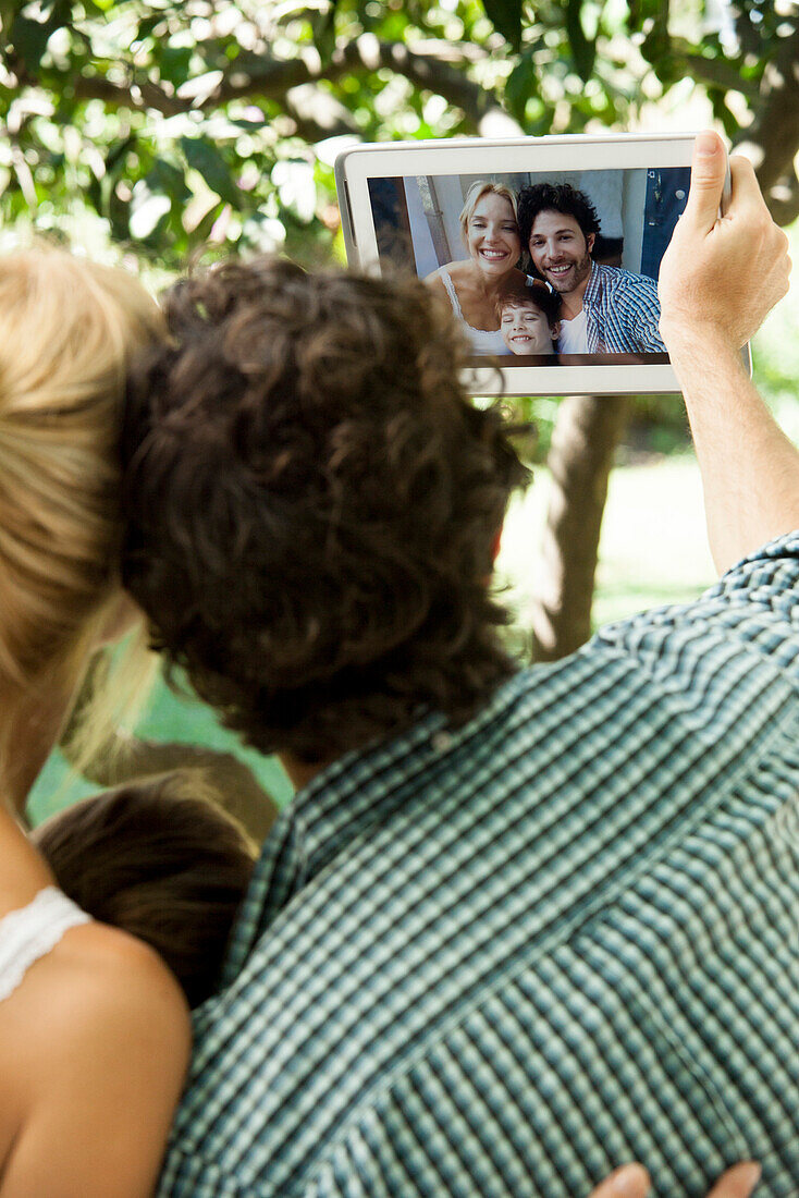 Family with one child posing for selfie taken with digital tablet