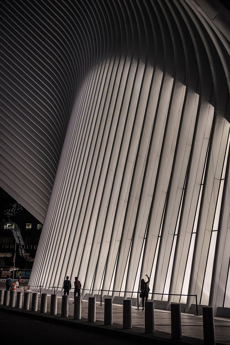 the Oculus, woman taking a photo of the facade at night, futuristic train station by famous architect Santiago Calatrava next to WTC Memorial, Manhattan, New York City, USA, United States of America