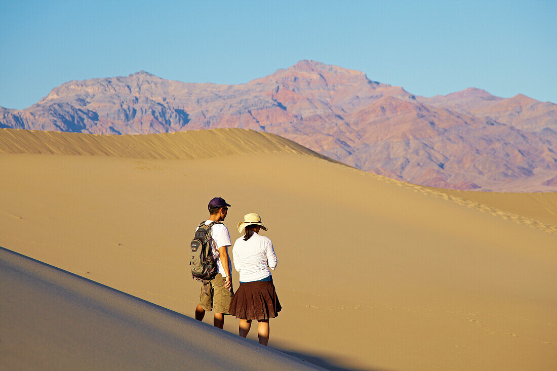 Couple hiking in the Mesquite Flat Sand Dunes at Stovepipe Wells Village , Amargosa Range , Death Valley National Park , California , U.S.A. , America