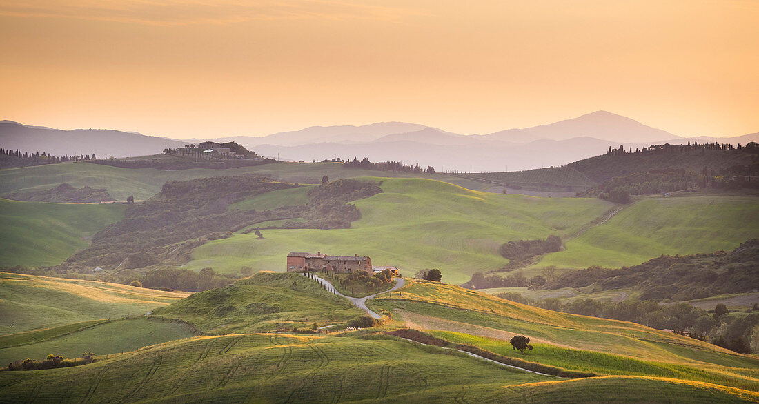 San Quirico d'Orcia, Tuscany, Italy. Podere surrounded by hills, during a warm sunrise.