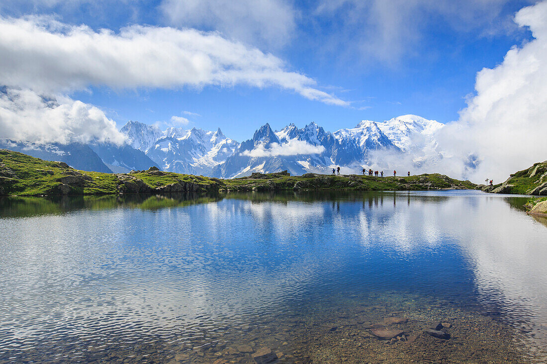 Low clouds and mist around Grandes Jorasses and Mount Blanc while hikers proceed on Lac De Cheserys Haute Savoie France Europe