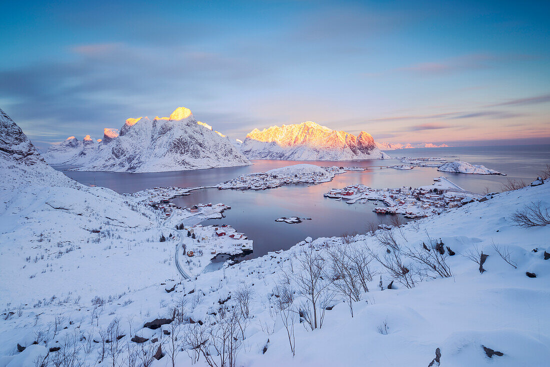 The pink colors of dawn frame the fishing villages and the frozen sea Reine Nordland Lofoten Islands Norway Europe