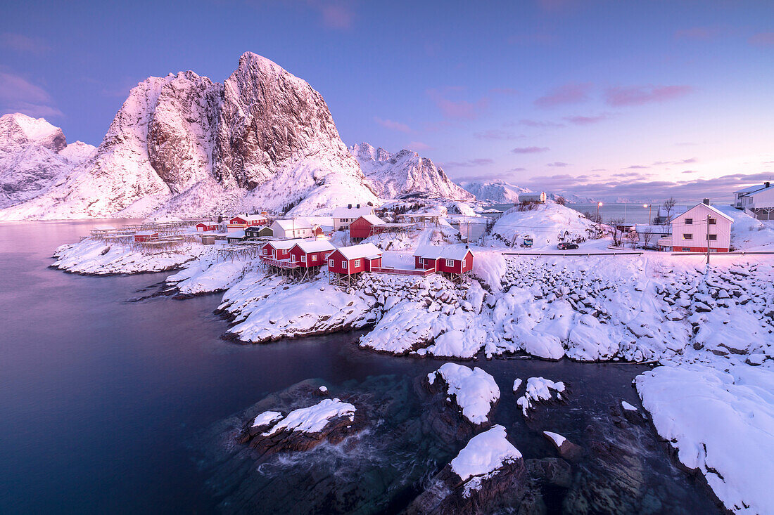 Pink sunrise on snowy peaks surrounded by the frozen sea around the village of Hamnoy Nordland Lofoten Islands Norway Europe