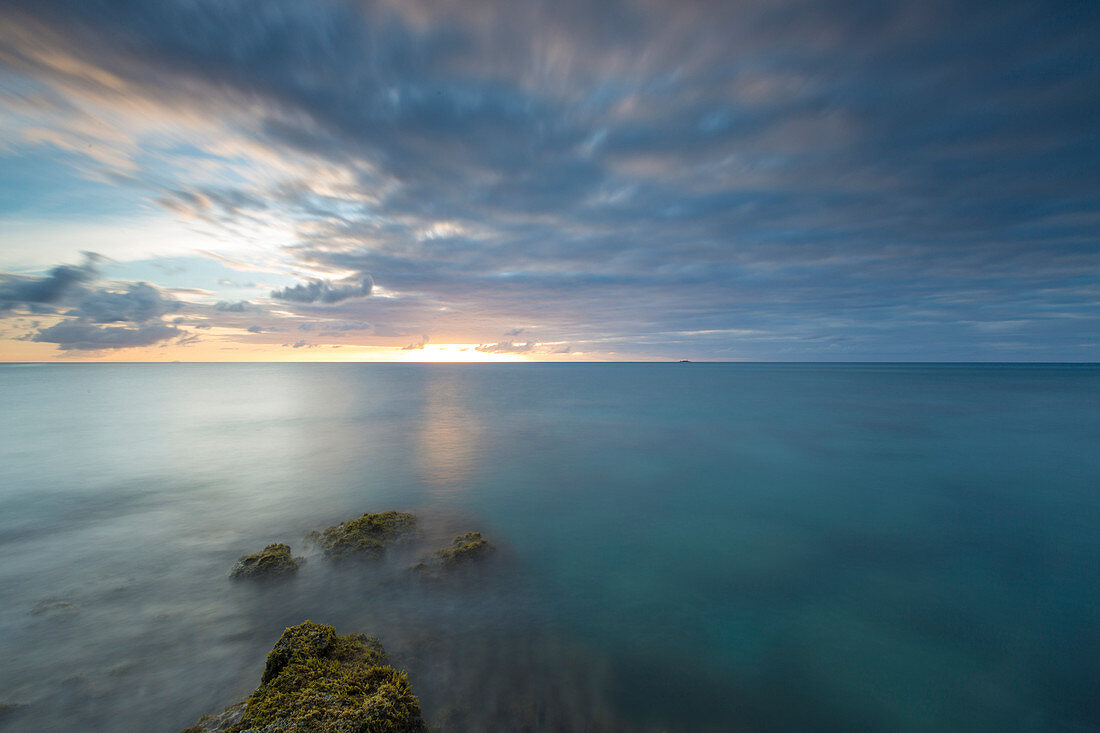 The lights of sunset are reflected in the blue sea Hawksbill Bay Caribbean Antigua and Barbuda Leeward Islands West Indies