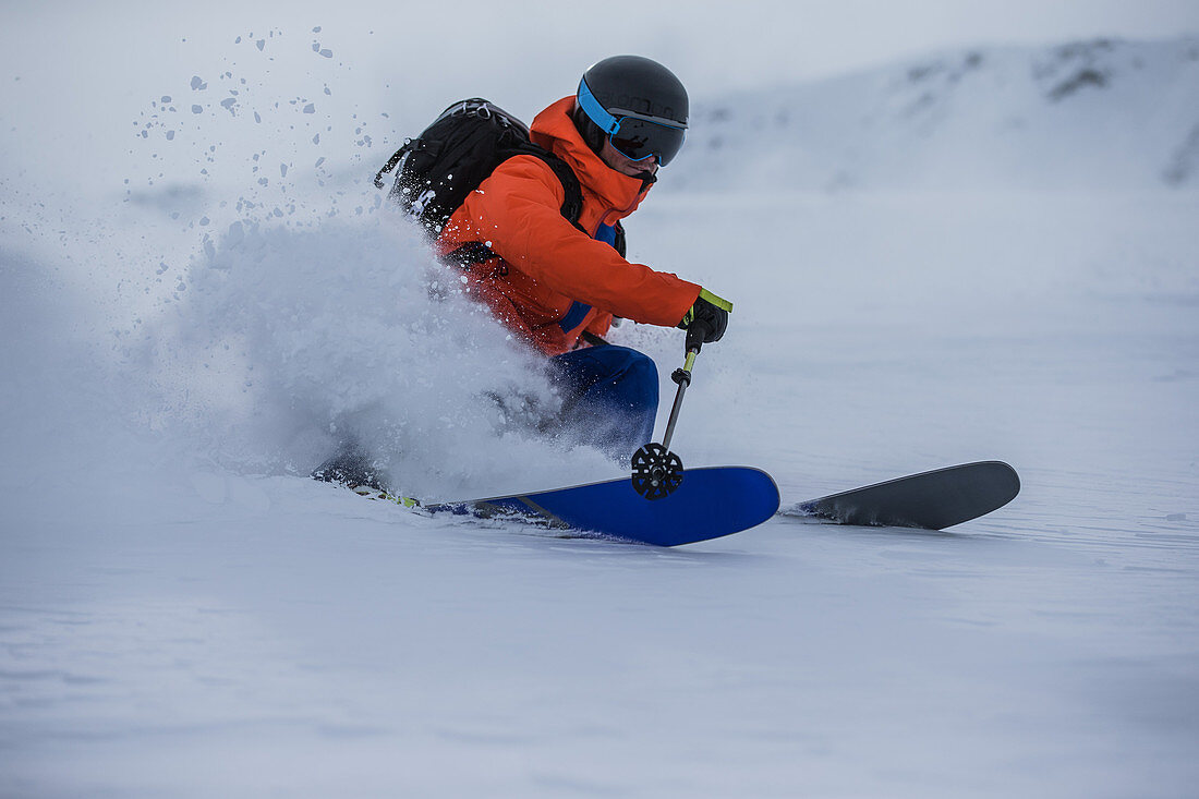 Young male skier riding through deep powder snow apart the slope, Andermatt, Uri, Switzerland