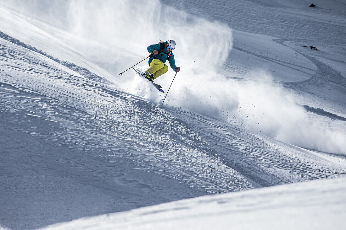 Young male skier jumping in the deep powder snow, Andermatt, Uri, Switzerland